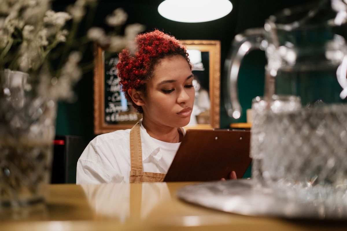 A café team member reviewing a clipboard behind the counter